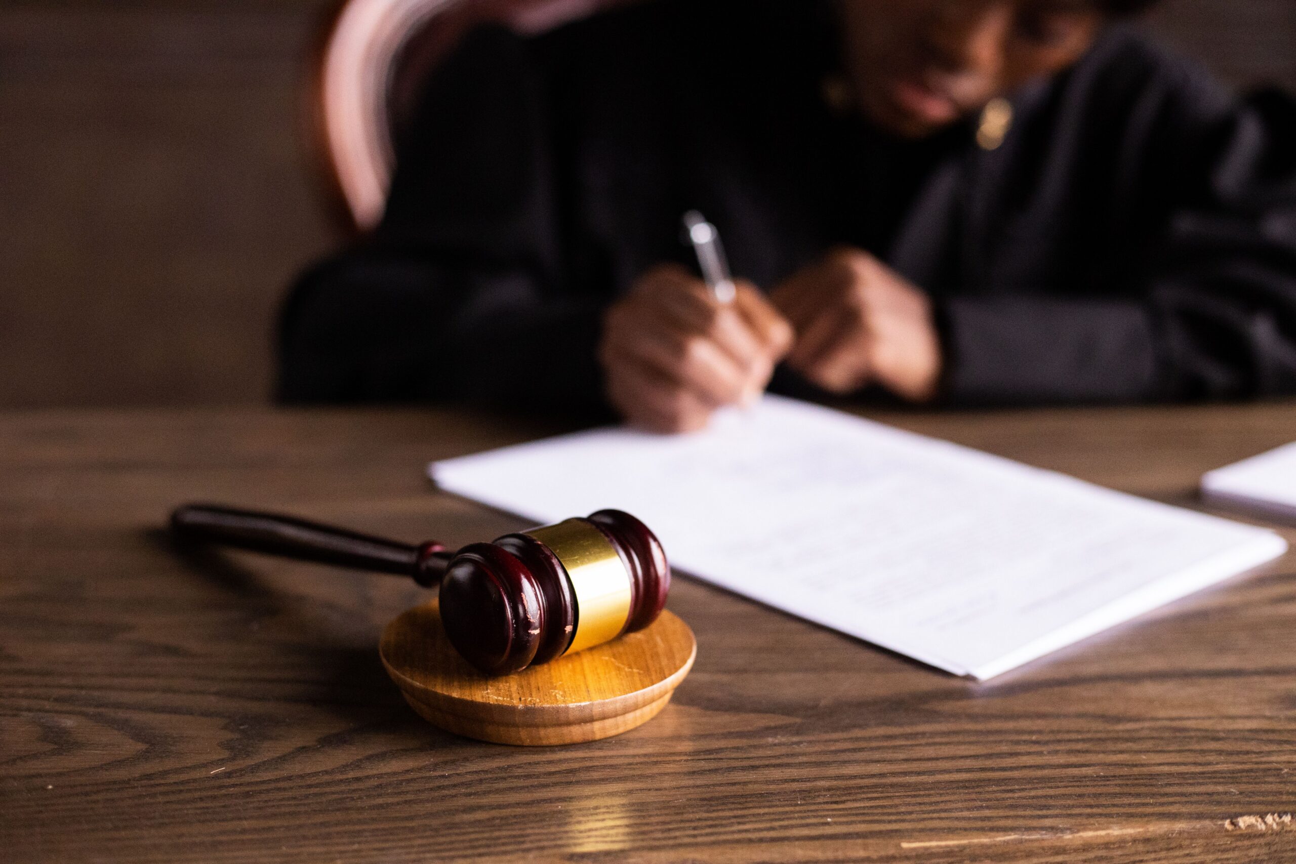 judge writing with gavel on desk